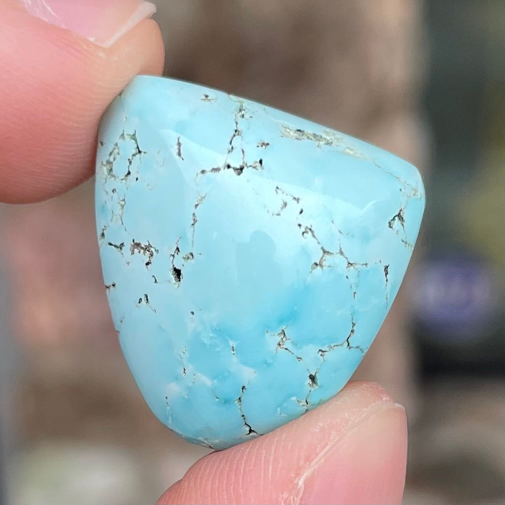 A loose, freeform cabochon cut light blue turquoise stone from Sleeping Beauty Mine, Arizona.