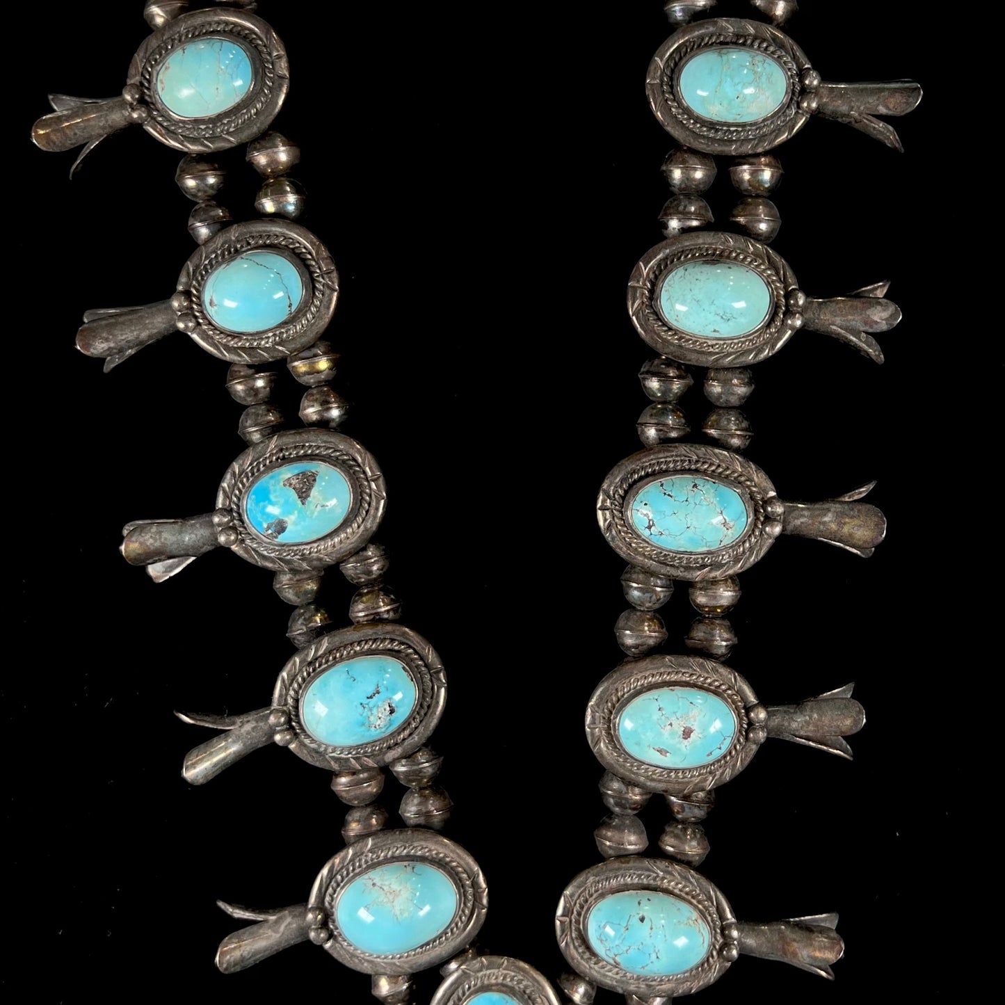 A silver Navajo style unisex squash blossom necklace set with oval cut Sleeping Beauty turquoise stones.