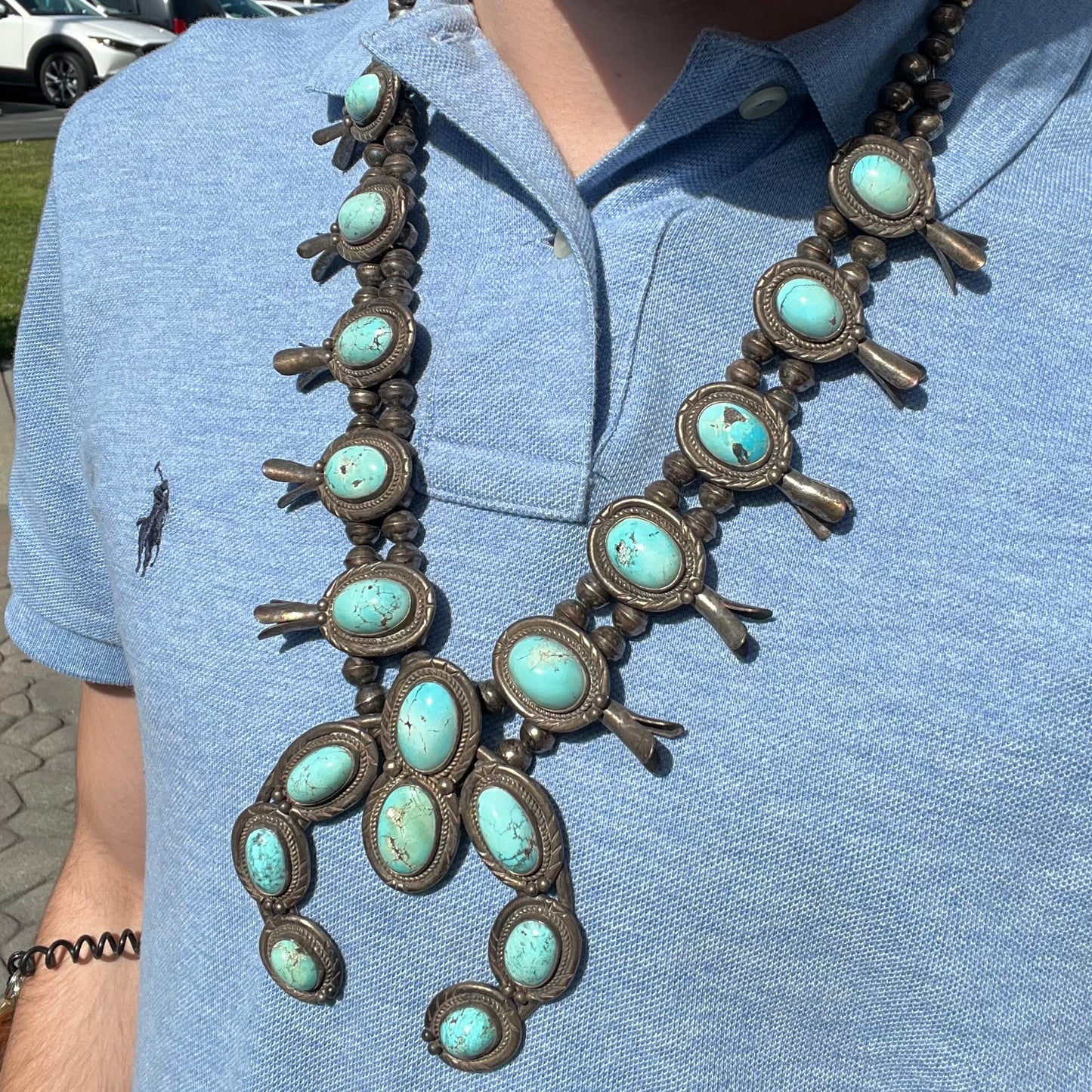A silver Navajo style unisex squash blossom necklace set with oval cut Sleeping Beauty turquoise stones.