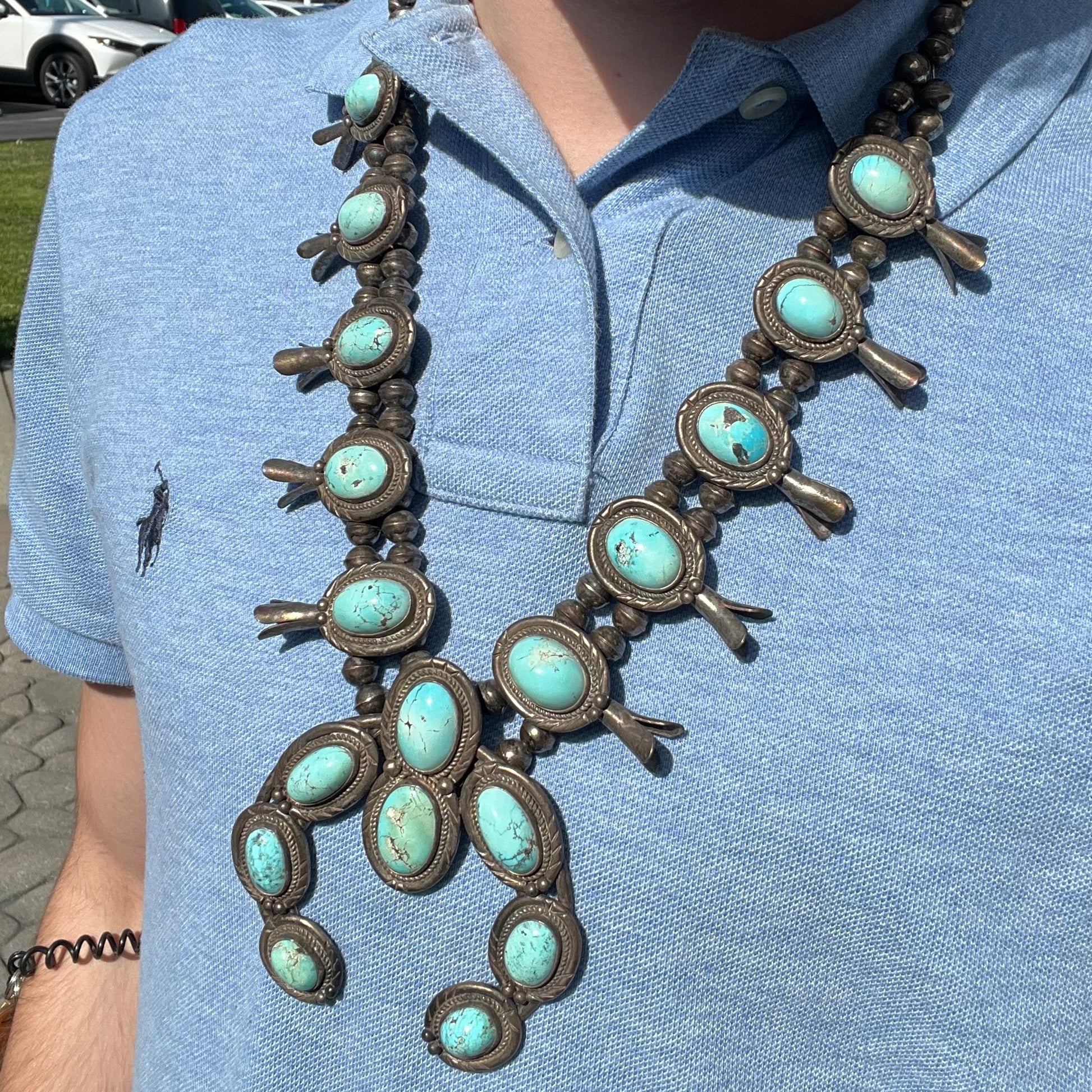 A silver Navajo style unisex squash blossom necklace set with oval cut Sleeping Beauty turquoise stones.