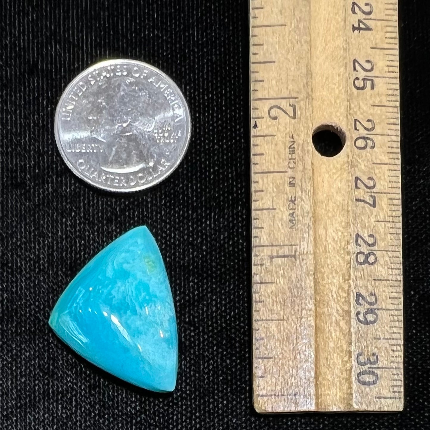 A loose triangular cabochon cut blue turquoise stone from the Sleeping Beauty Mine in Arizona.