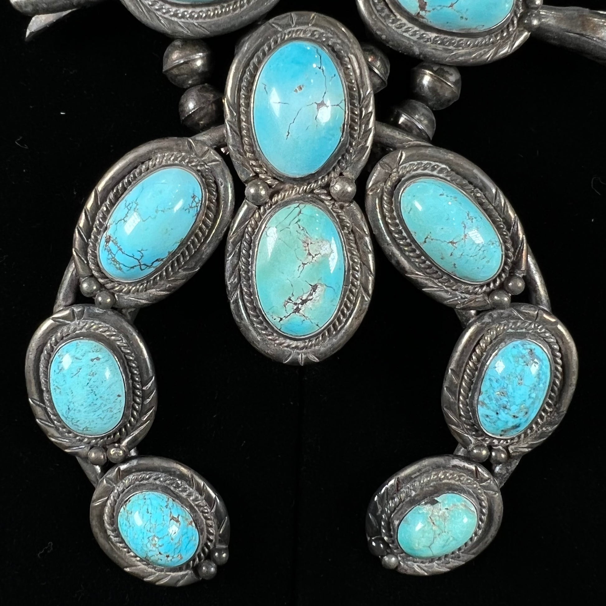 A silver Navajo style unisex squash blossom necklace set with oval cut Sleeping Beauty turquoise stones.
