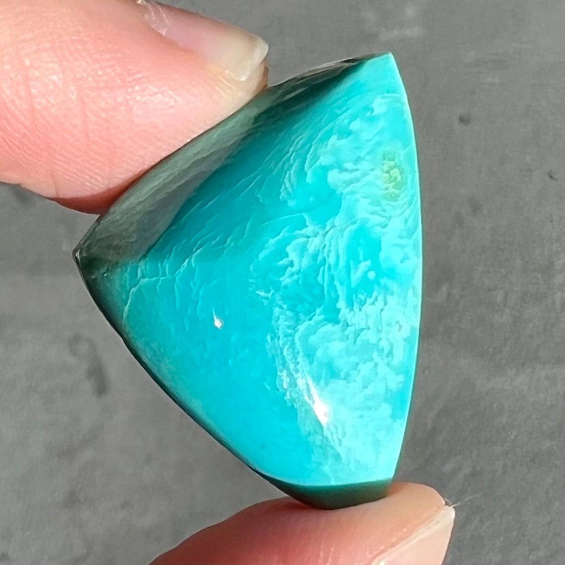 A loose triangular cabochon cut blue turquoise stone from the Sleeping Beauty Mine in Arizona.