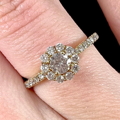 A ladies' diamond halo engagement ring cast in yellow gold.  The center stone is a 0.19ct round cut natural diamond.