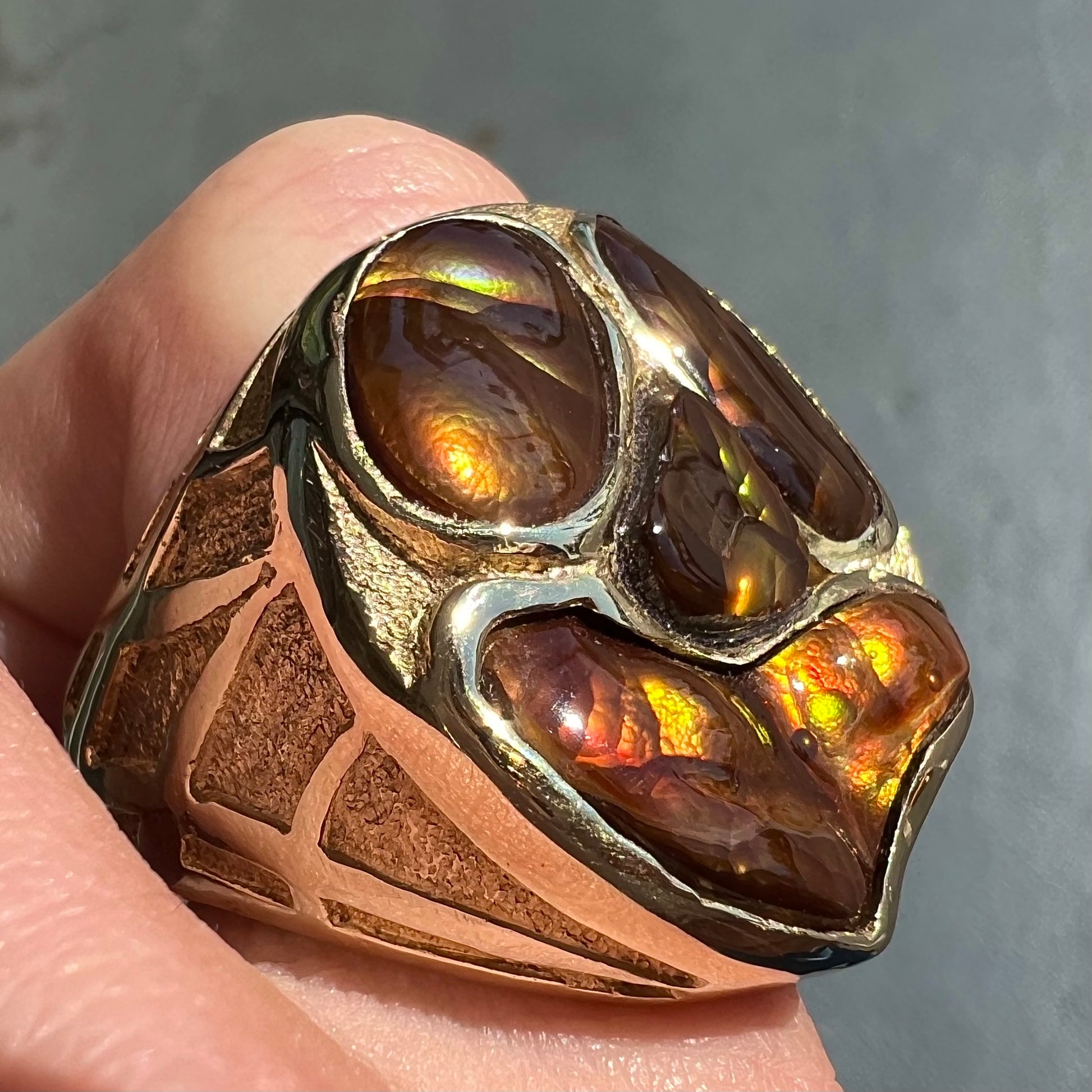 A yellow gold men's thug ring set with four fire agate stones resembling a spooky face.