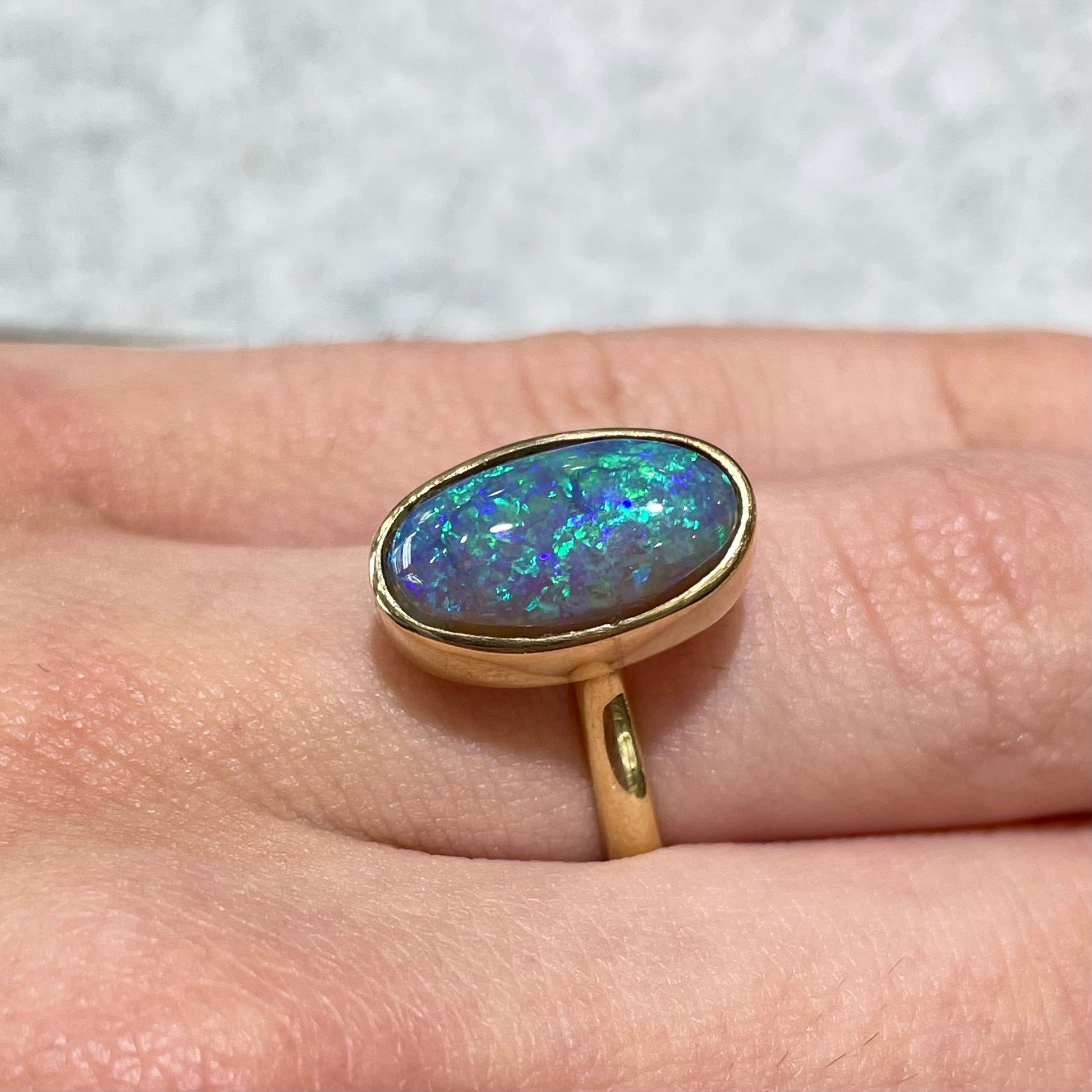 A simple yellow gold solitaire ring with a bezel set Lightning Ridge black crystal opal from Australia.