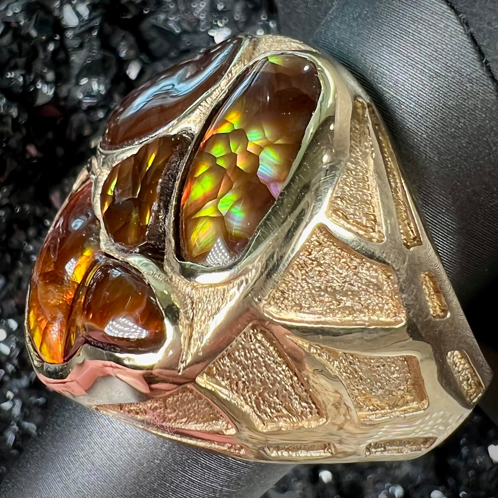 A yellow gold men's thug ring set with four fire agate stones resembling a spooky face.