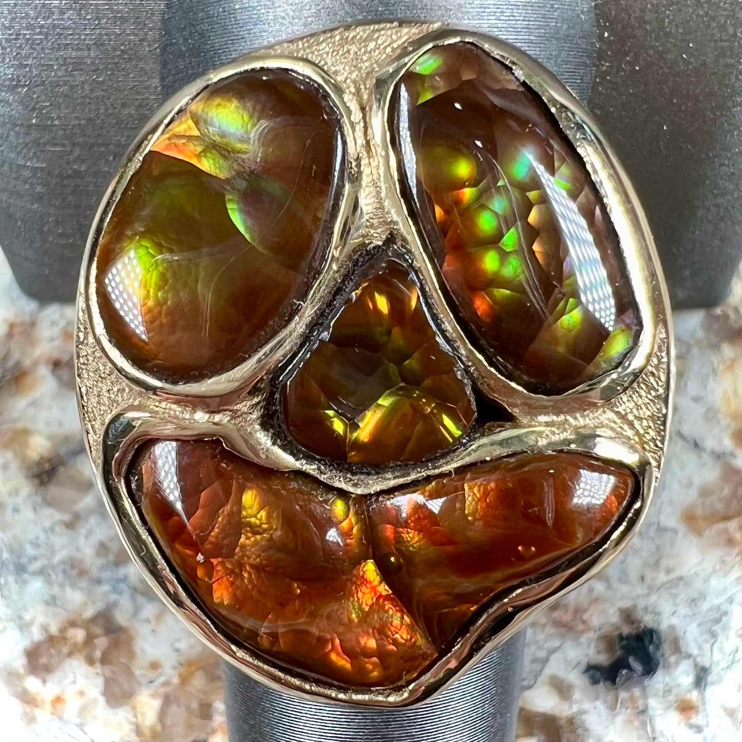 A yellow gold men's thug ring set with four fire agate stones resembling a spooky face.