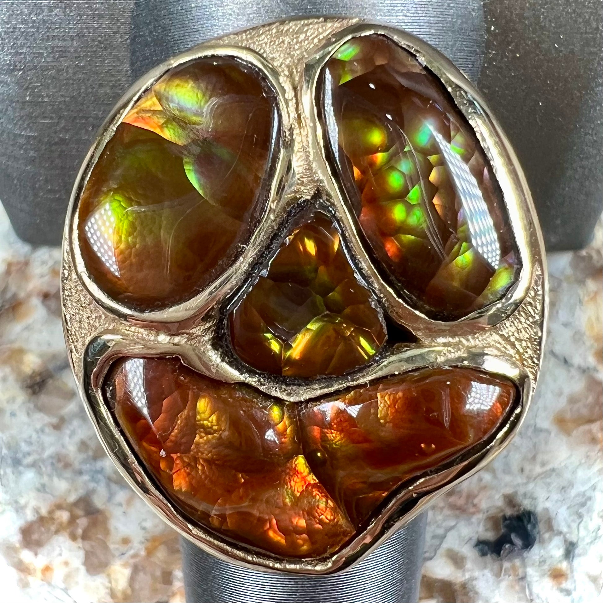 A yellow gold men's thug ring set with four fire agate stones resembling a spooky face.