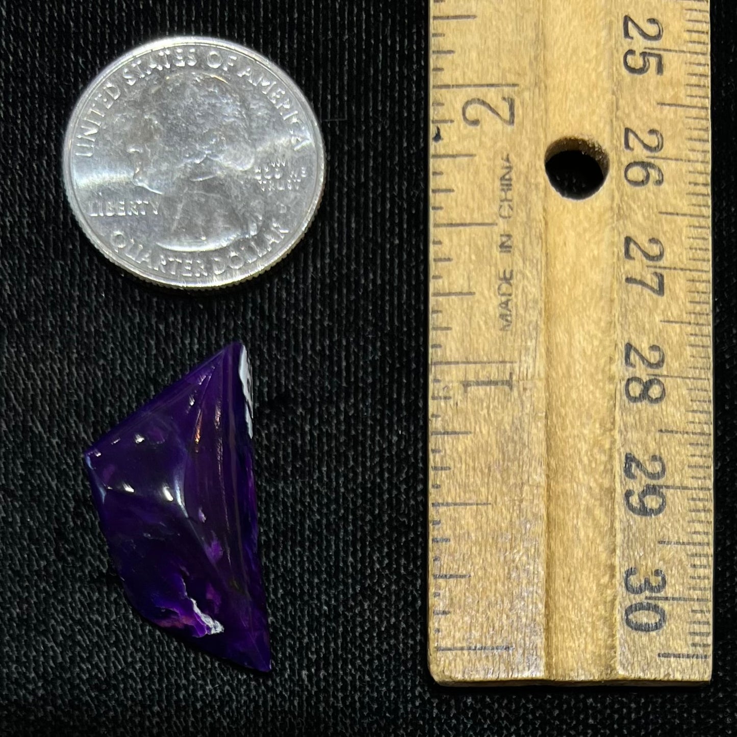 A freeform cabochon cut piece of dark purple sugilite.