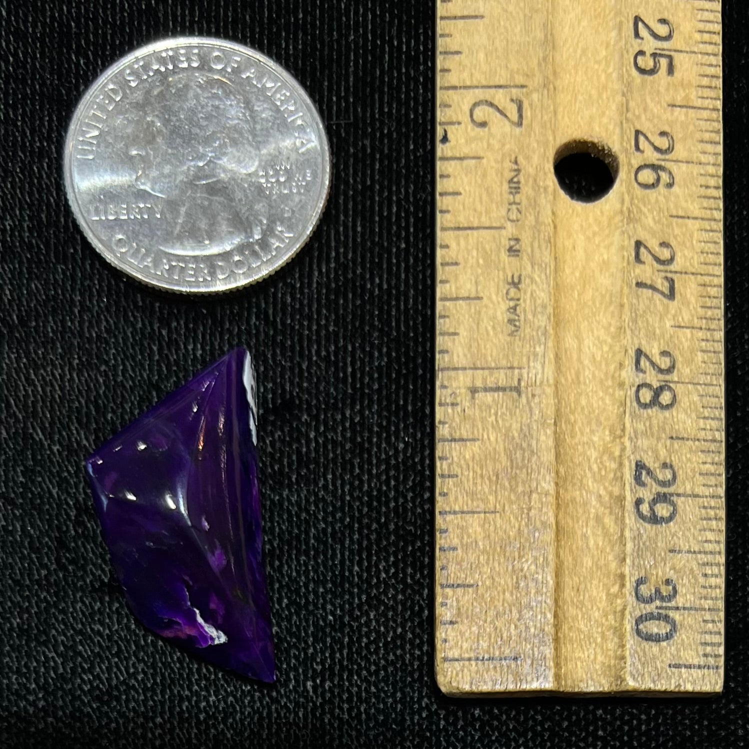 A freeform cabochon cut piece of dark purple sugilite.