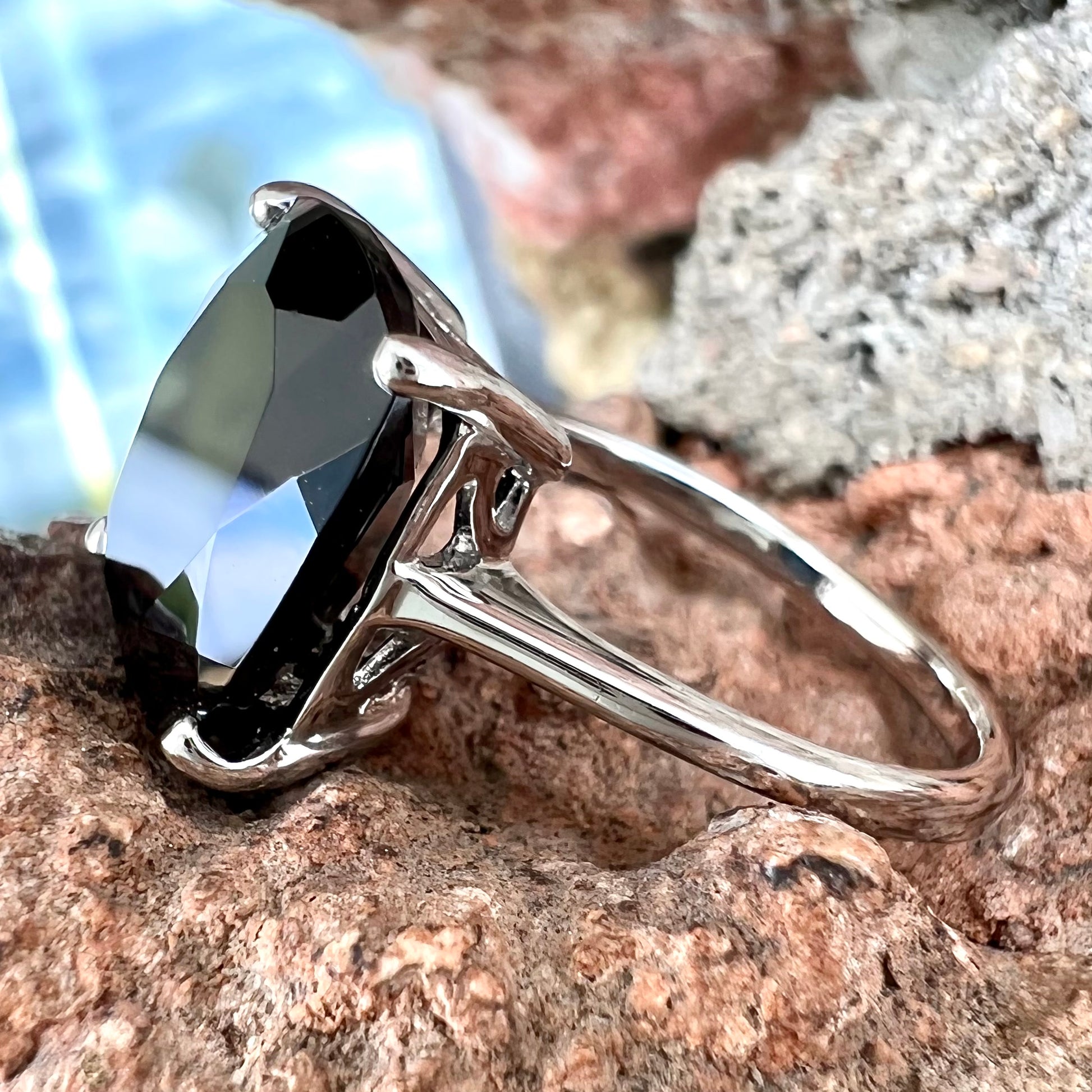 A cushion cut black spinel prong set in a sterling silver solitaire ring.