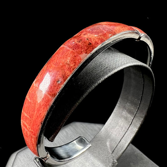 An adjustable stainless steel cuff bracelet inlaid with polished spiny oyster shell.