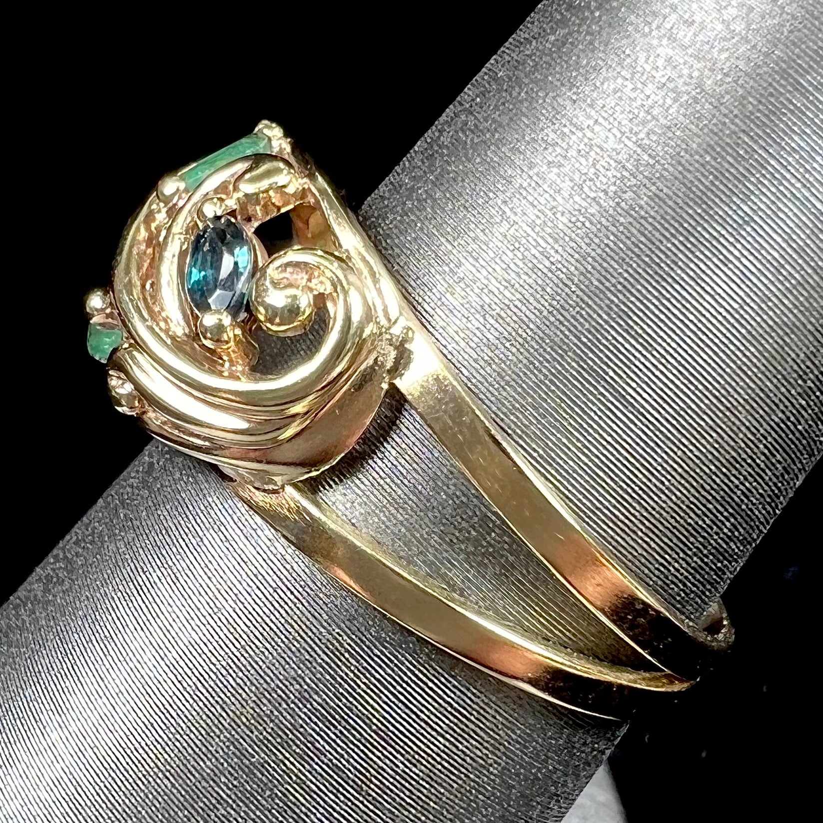 A yellow gold ladies' ring featuring the motif of a flower with leaves set with emeralds, rubies, sapphires, and a  diamond.