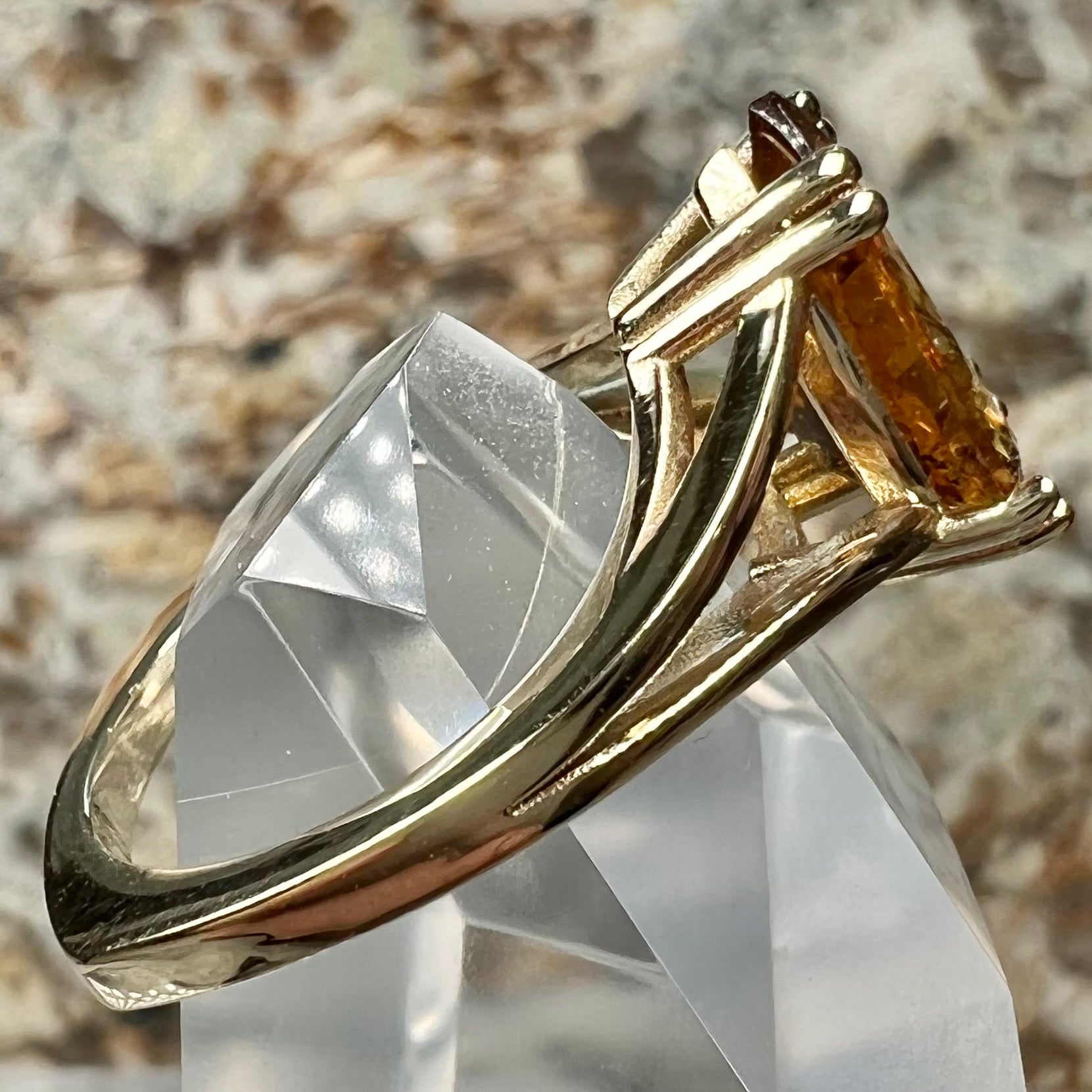 A gold split Euro shank solitaire ring set with an orange pear shape hessonite garnet stone.