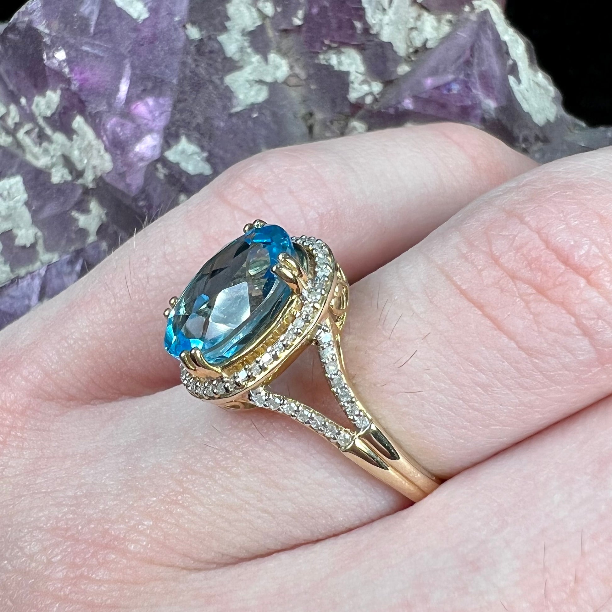An oval cut Swiss blue topaz and diamond pave split shank ring in yellow gold.