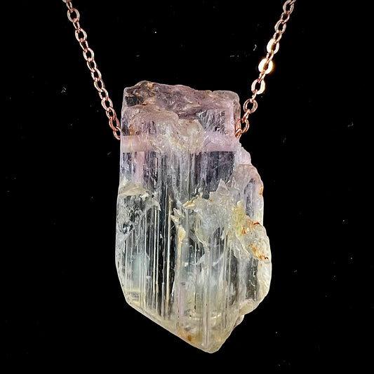 A drilled bicolor spodumene crystal hanging on a copper cable chain.  The crystal is pink and yellow, or kunzite and triphane respectively.