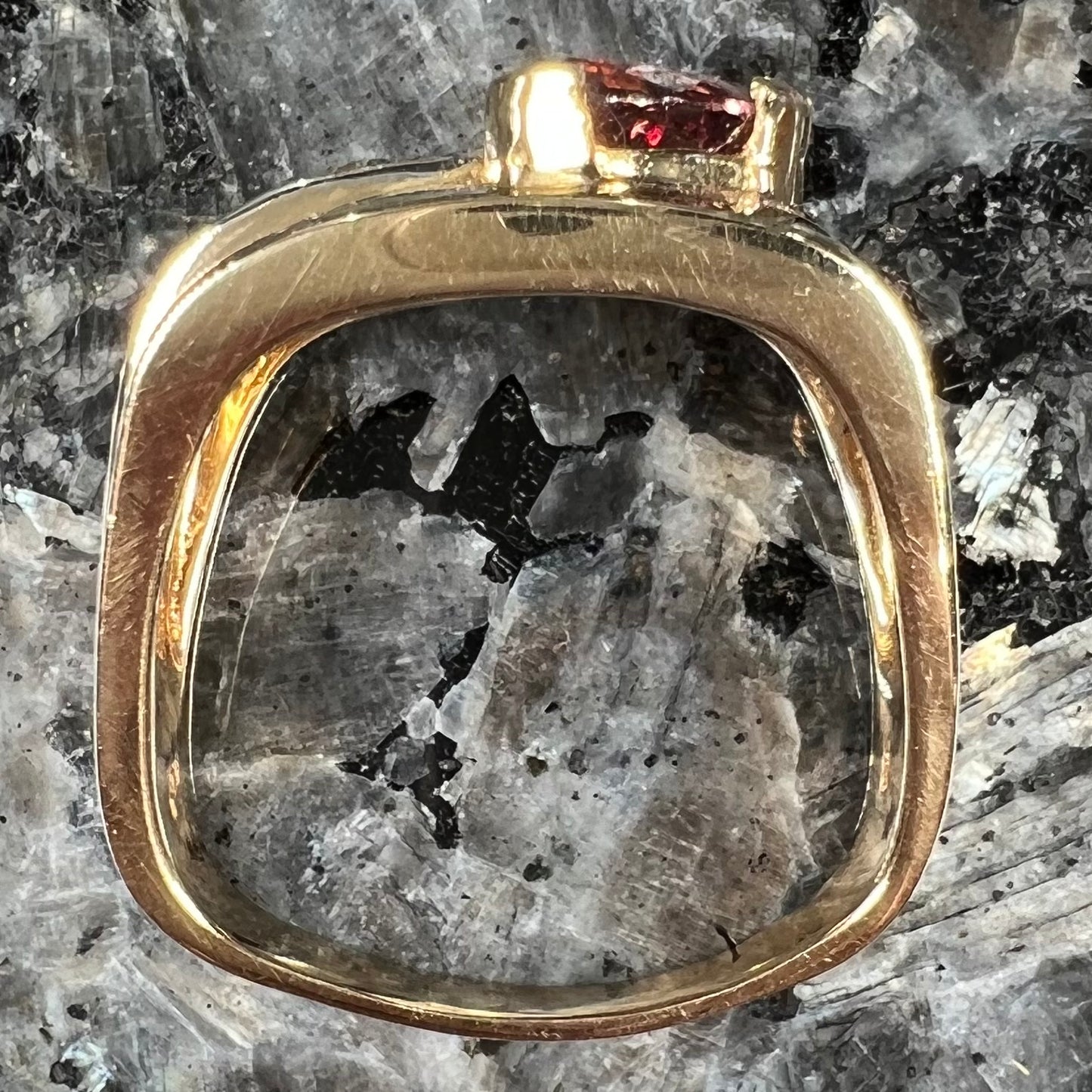 A men's gold pink tourmaline ring.  Set next to the trillion cut tourmaline is a row of three round white sapphires.