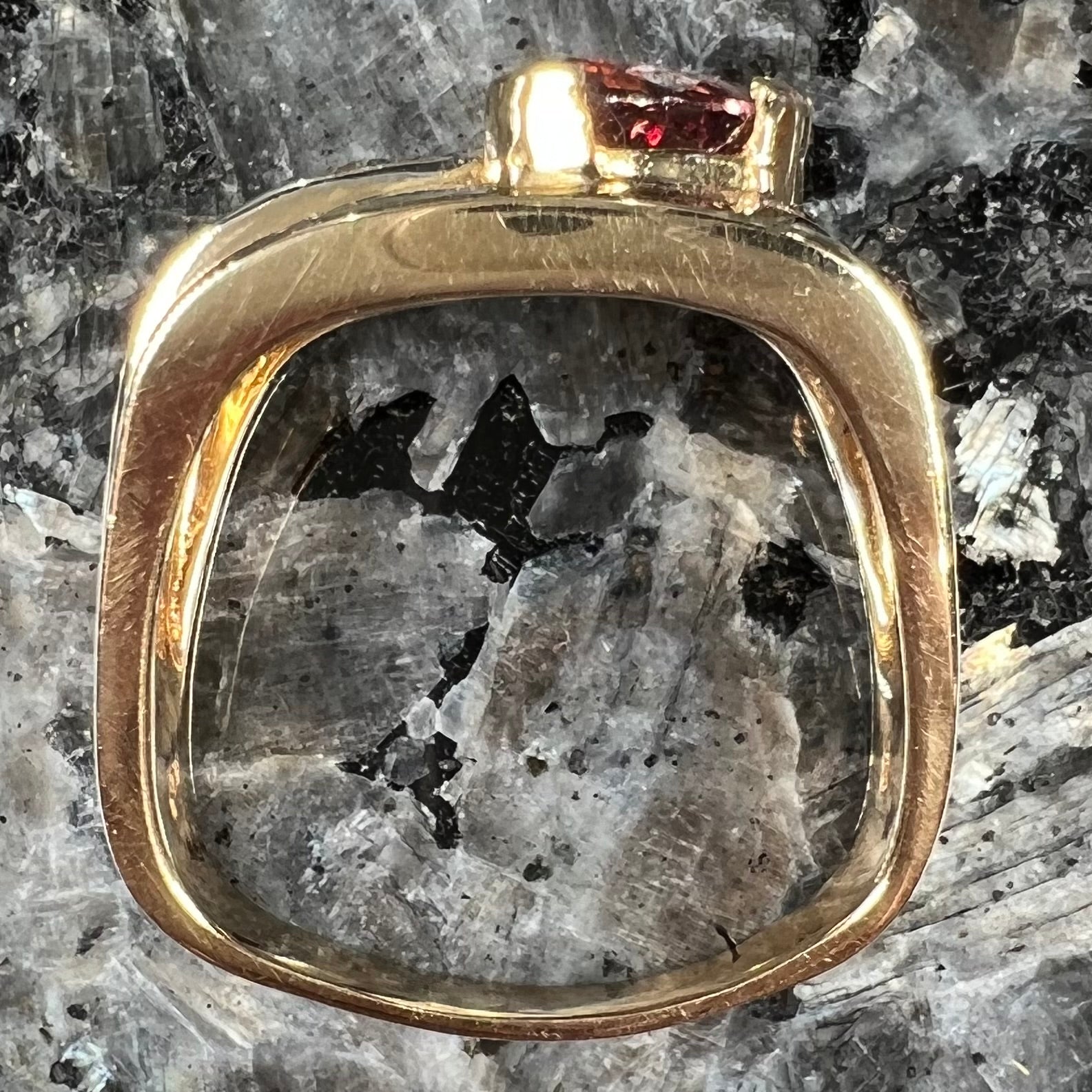 A men's gold pink tourmaline ring.  Set next to the trillion cut tourmaline is a row of three round white sapphires.