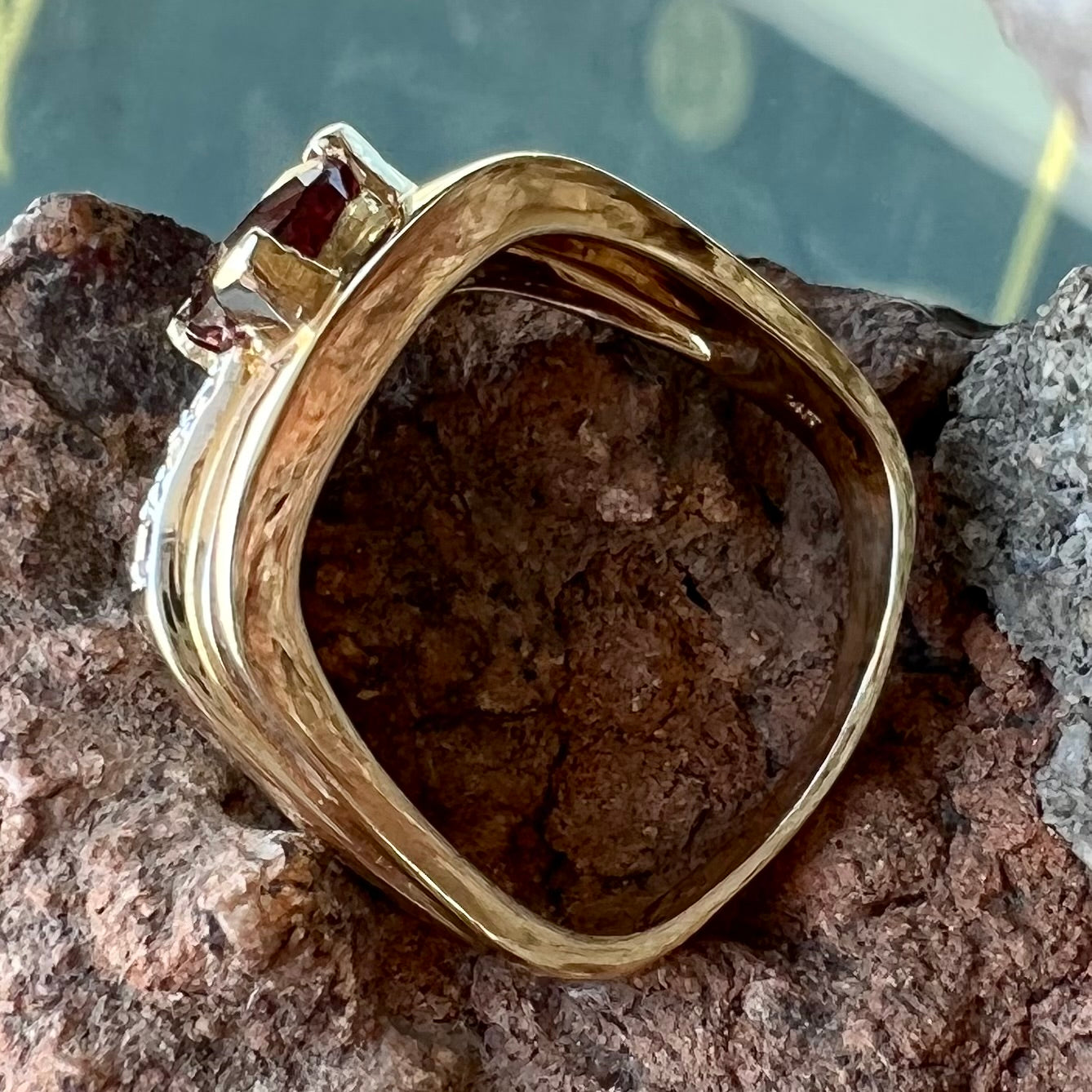 A men's gold pink tourmaline ring.  Set next to the trillion cut tourmaline is a row of three round white sapphires.