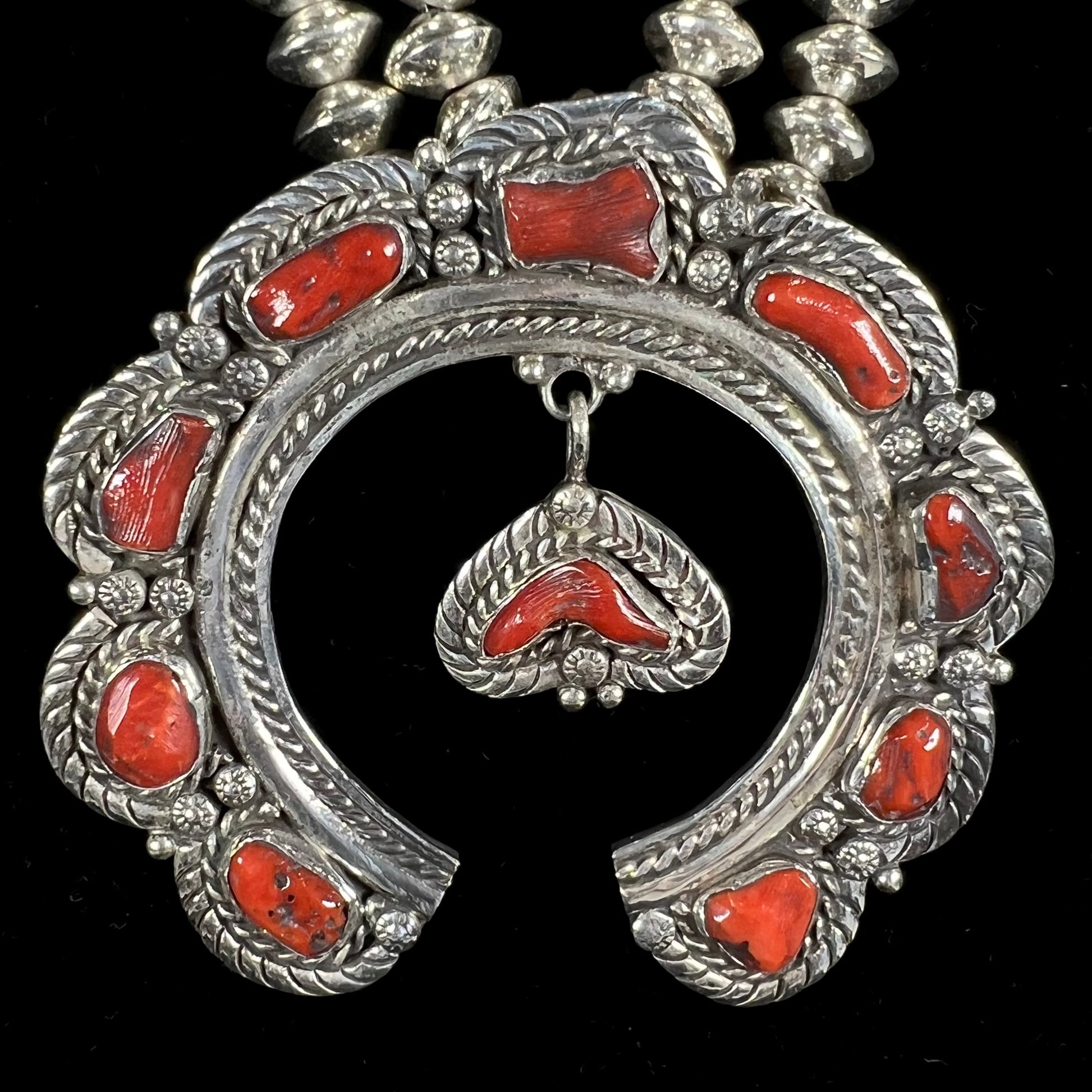 A Navajo style squash blossom necklace set with red coral branches, handmade by artist Delbert Chatter.