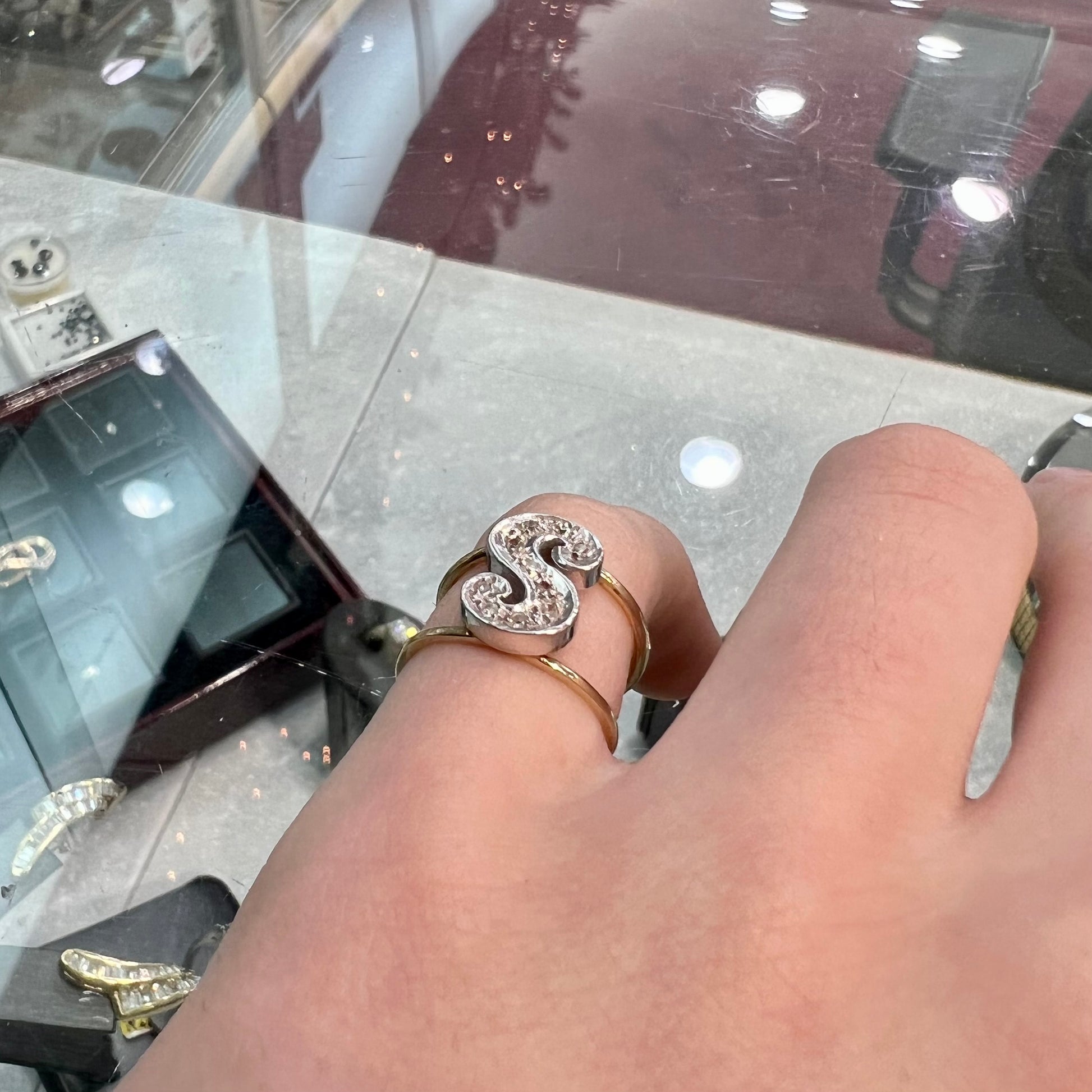A two tone white and yellow gold initial ring of the letter "S" set with diamonds.