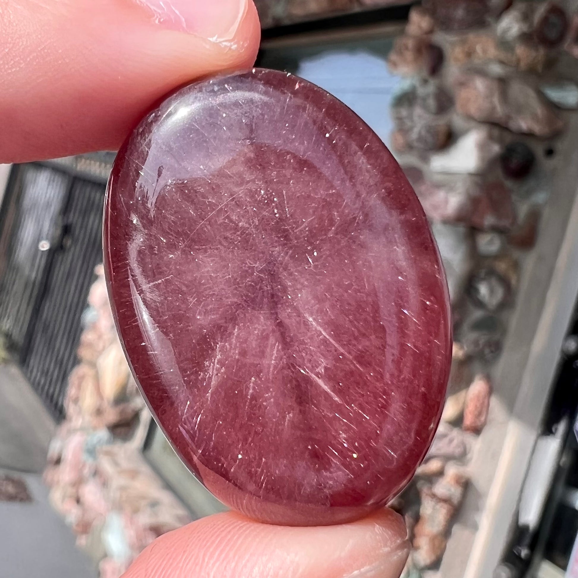A large, oval cabochon cut strawberry quartz.  The stone has a trapiche star-like pattern.