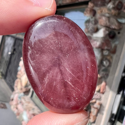 A large, oval cabochon cut strawberry quartz.  The stone has a trapiche star-like pattern.