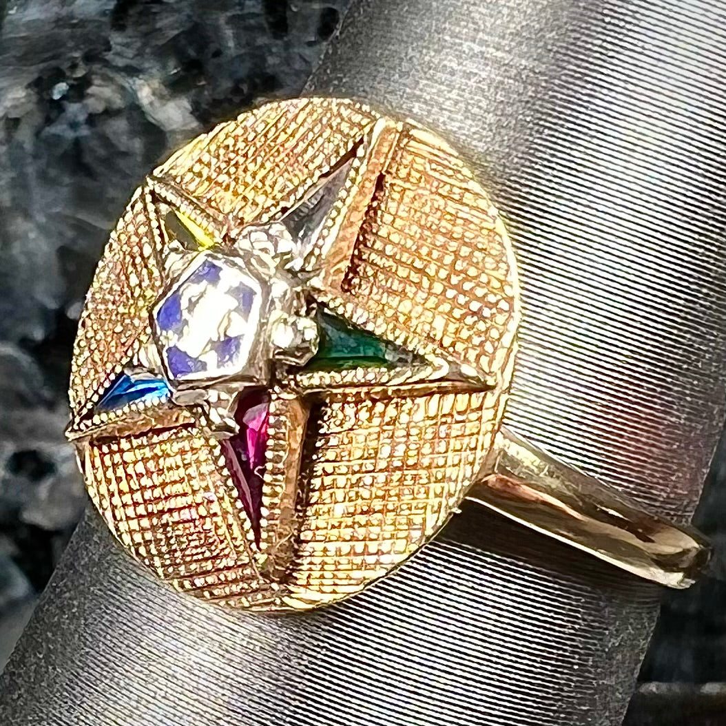 A gold ring set with multicolored synthetic sapphires forming a star with a blue enameled center, symbolizing the Order of the Eastern Star.