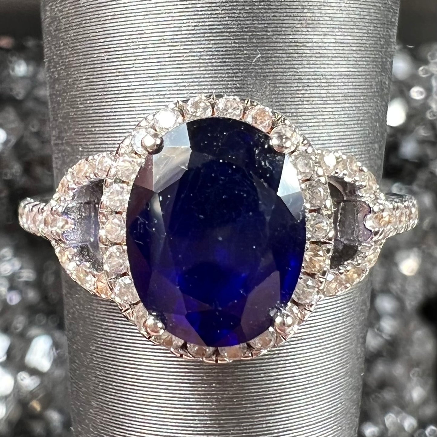 A sterling silver, white zircon halo ring set with an oval cut blue sapphire.