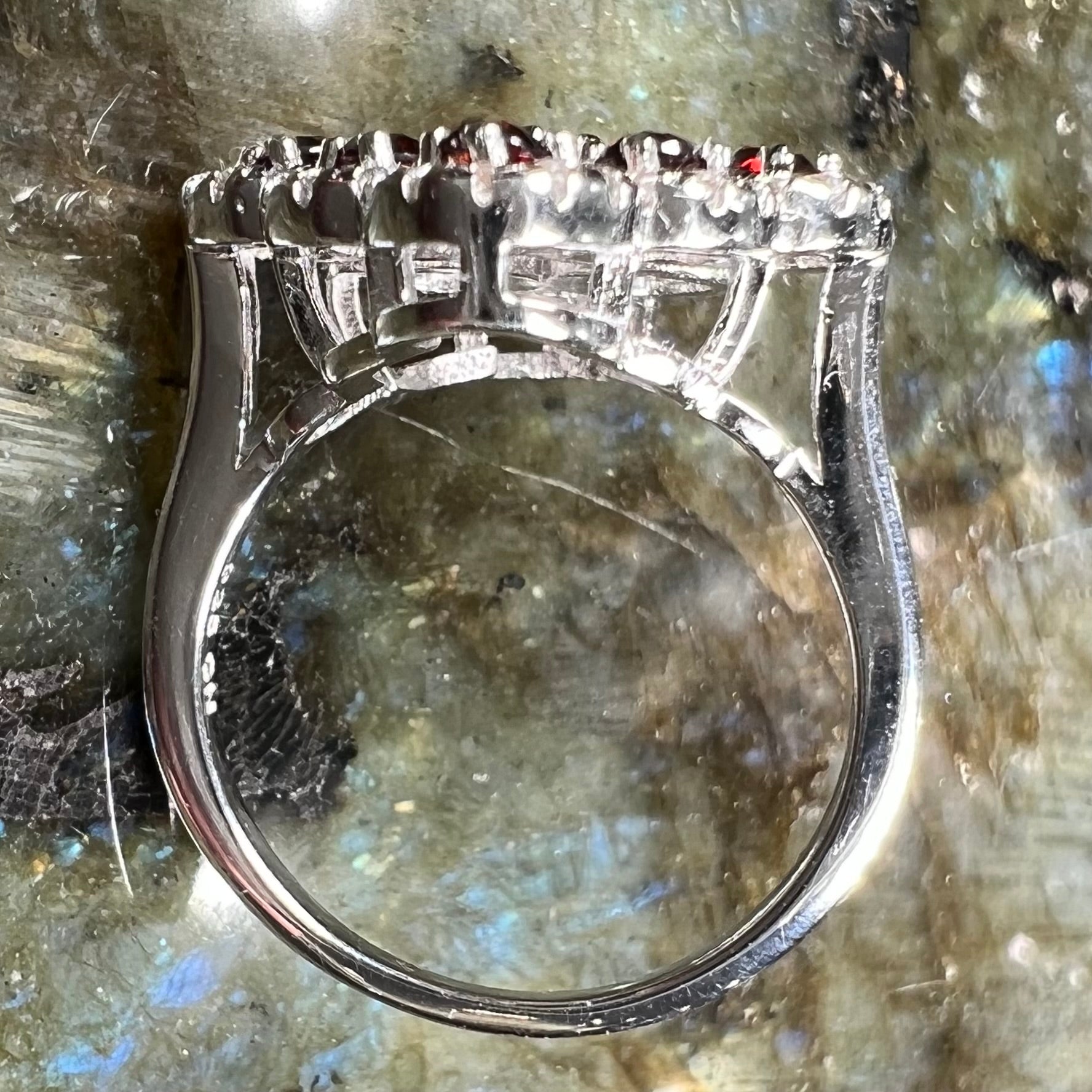 A sterling silver cluster ring set with round almandine garnet main stones and white zircon accents.
