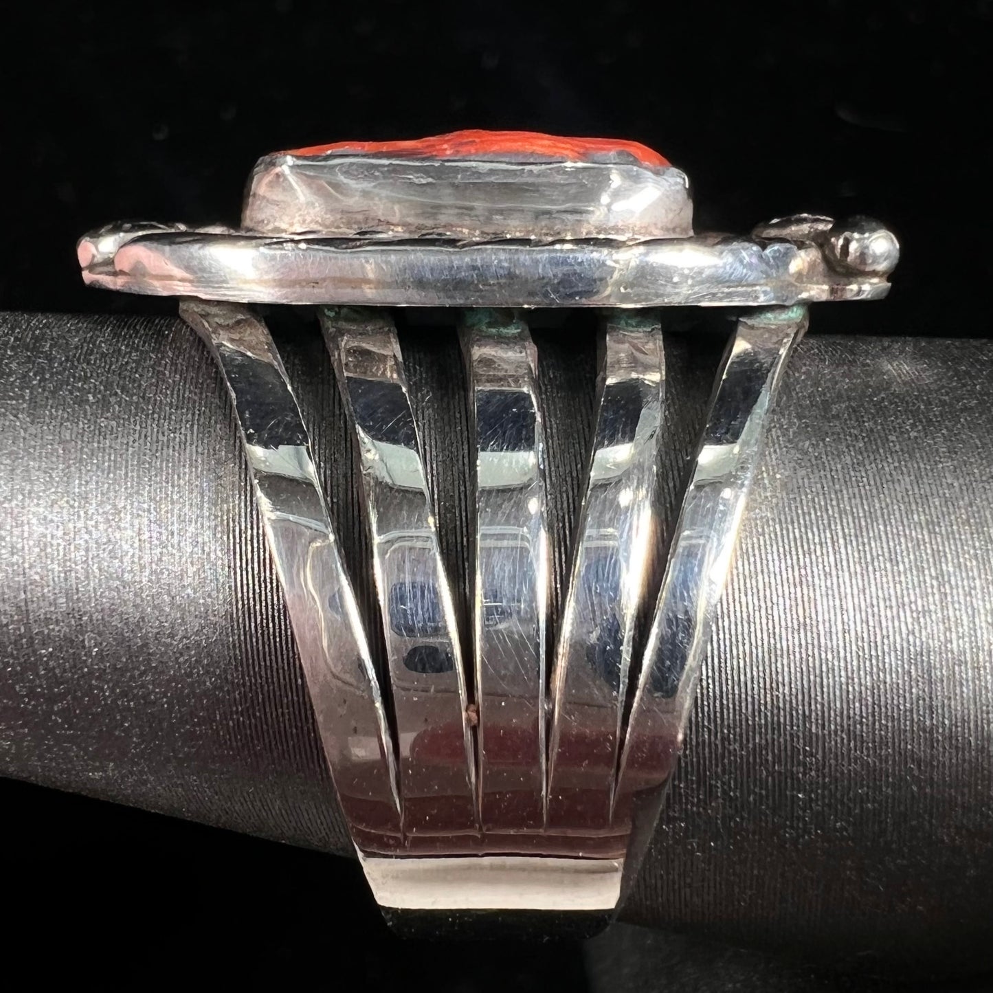 A sterling silver ring set with a polished red coral branch handmade by Navajo artist, Delbert Chatter.