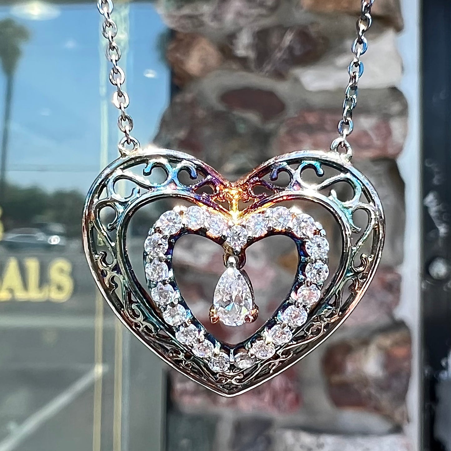 A sterling silver and cubic zirconia heart necklace.  The silver has a rainbow patina.