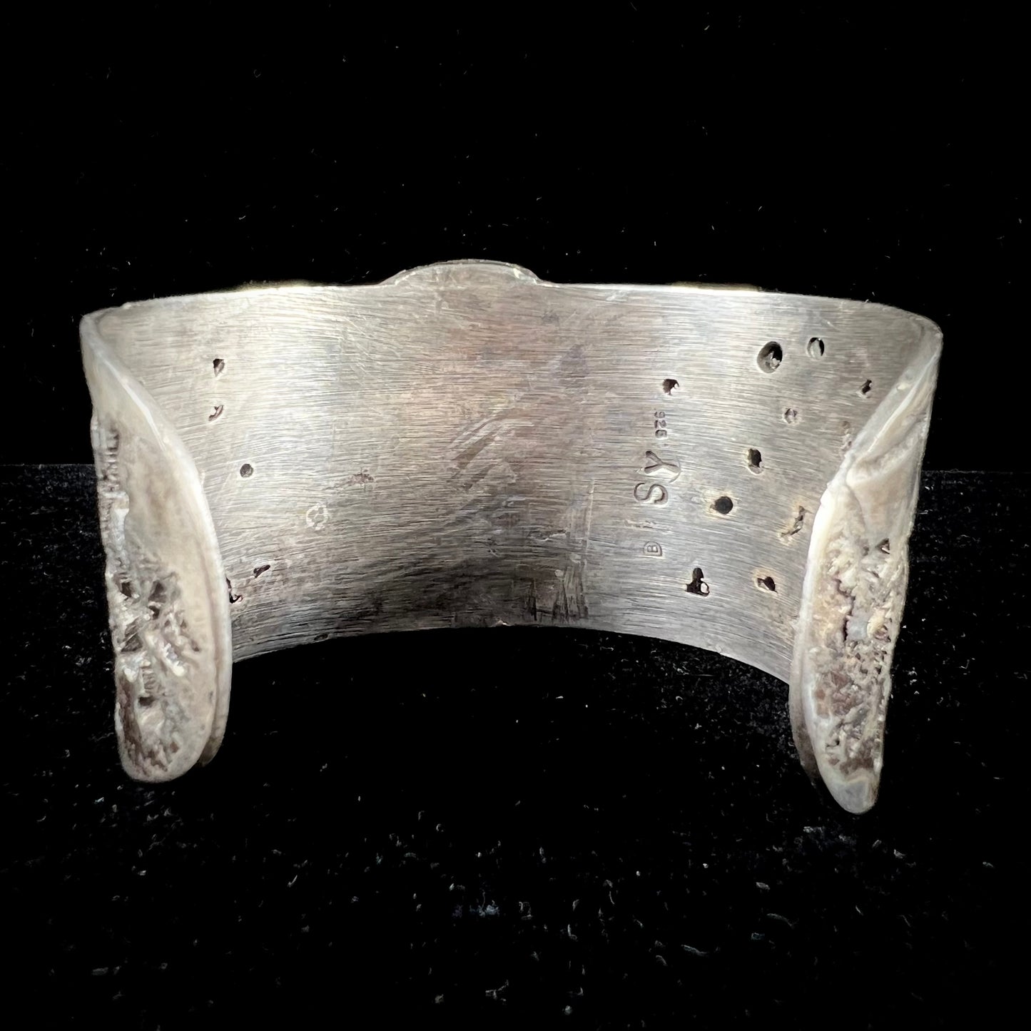 A men's sterling silver cuff bracelet infused with copper and set with a green turquoise stone from Carico Lake, Nevada.