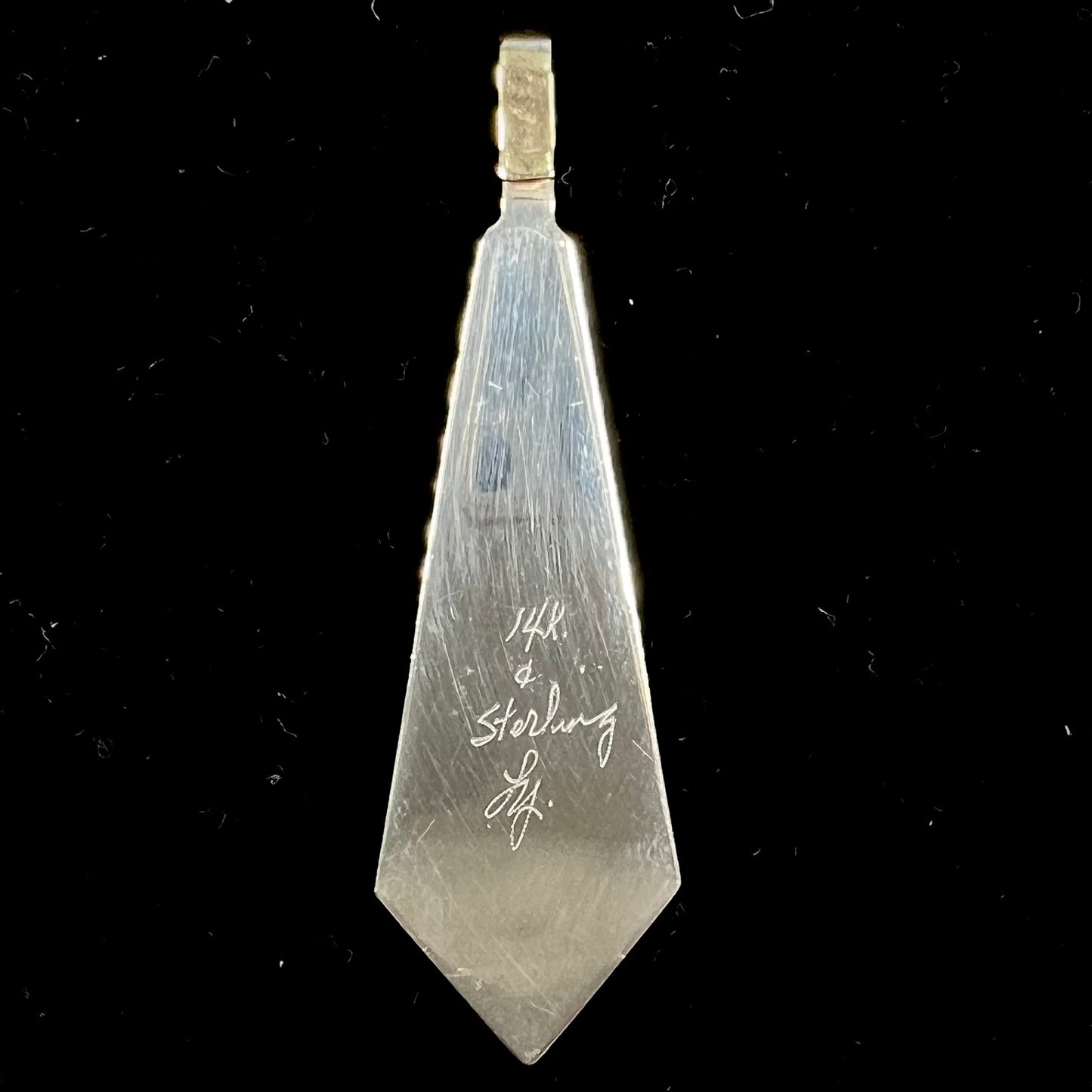 A yellow gold and sterling silver pendant inlaid with turquoise, coral, and lapis lazuli stones.  The piece is made by an unknown Native American artist and signed with the initials "LY".