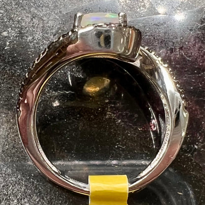 A sterling silver ring set with round black spinel stones and an oval cut, faceted Ethiopian opal.
