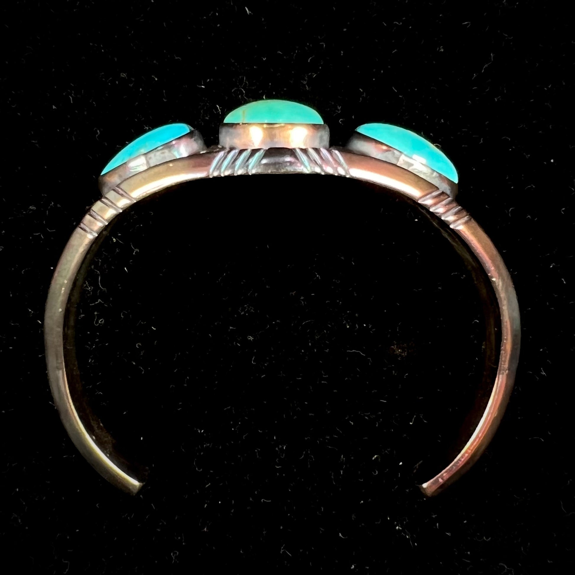 A men's Navajo three stone turquoise cuff bracelet handmade by artist, Dean Brown.  The silver has an iridescent purple patina.