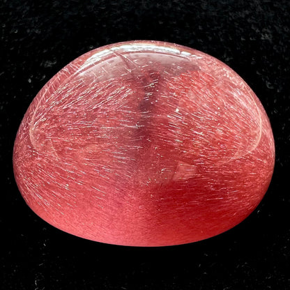 A large, oval cabochon cut strawberry quartz.  The stone has a trapiche star-like pattern.