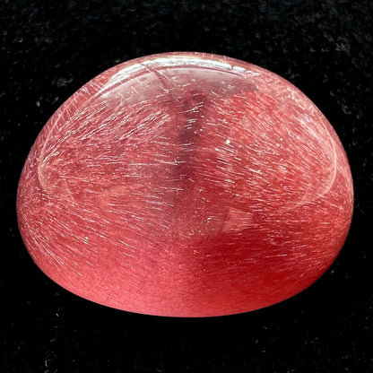 A large, oval cabochon cut strawberry quartz.  The stone has a trapiche star-like pattern.