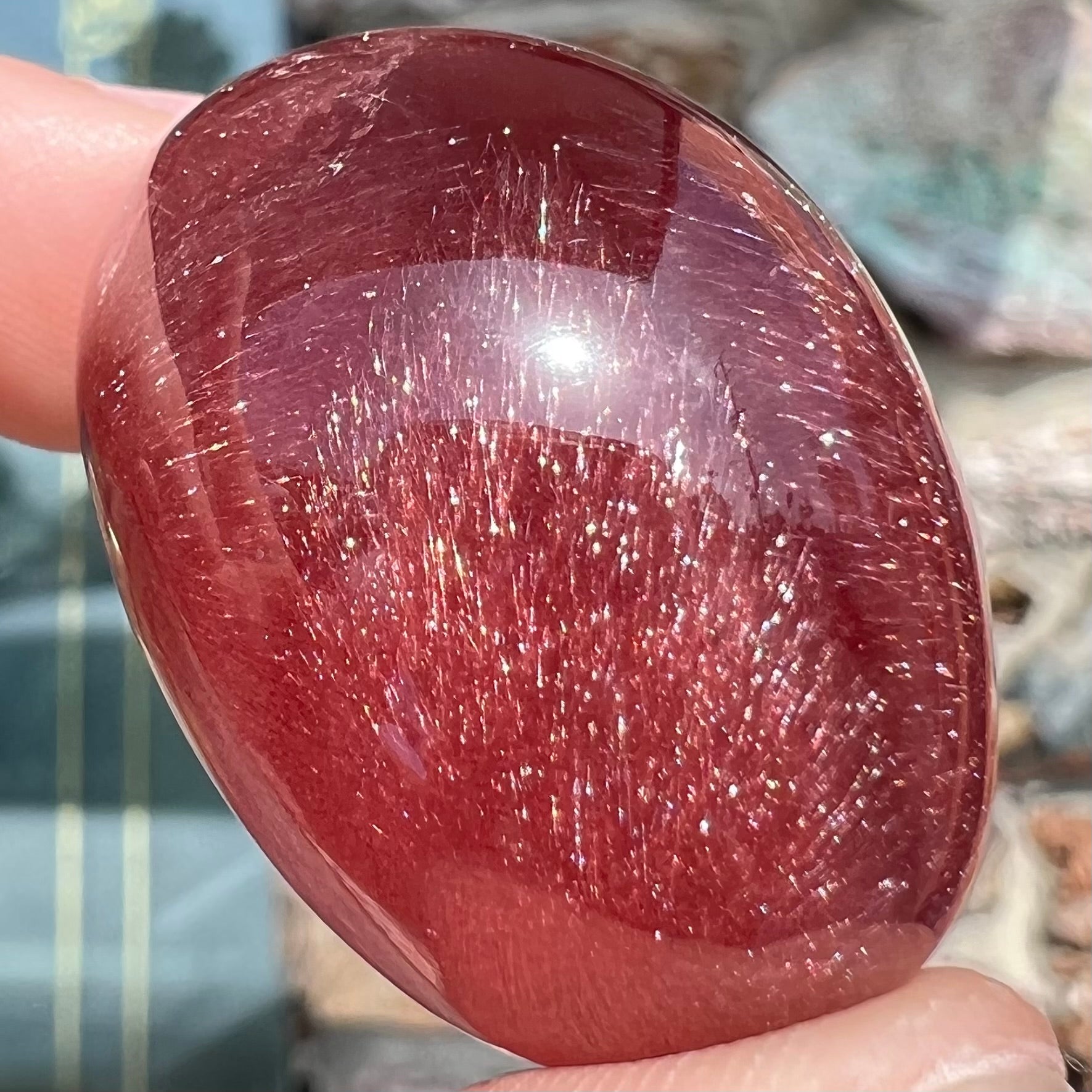 A large, oval cabochon cut strawberry quartz.  The stone has a trapiche star-like pattern.