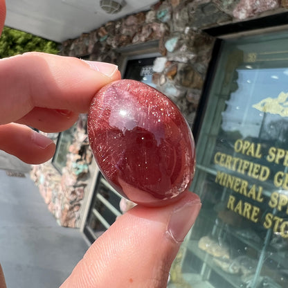 A large, oval cabochon cut strawberry quartz.  The stone has a trapiche star-like pattern.