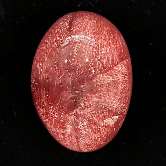 A large, oval cabochon cut strawberry quartz.  The stone has a trapiche star-like pattern.