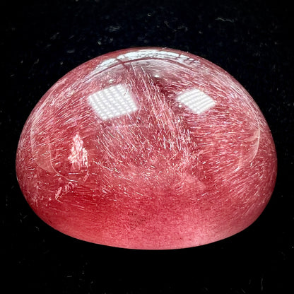 A large, oval cabochon cut strawberry quartz.  The stone has a trapiche star-like pattern.
