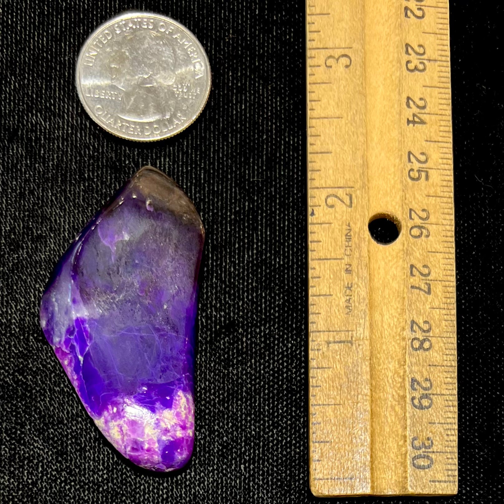 A loose, polished sugilite specimen displaying a blend of different shades of purple.