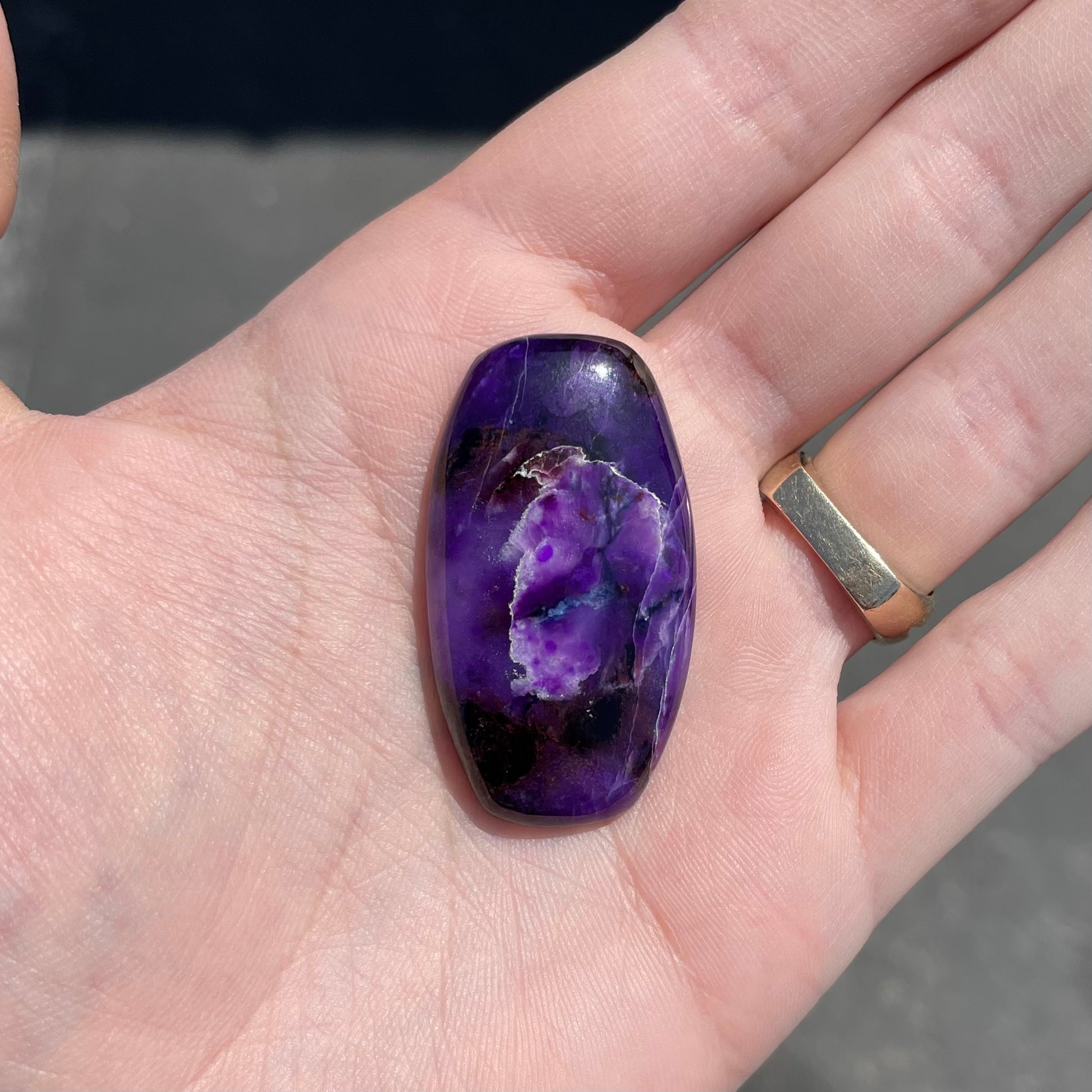 A loose, barrel cabochon cut purple sugilite stone.