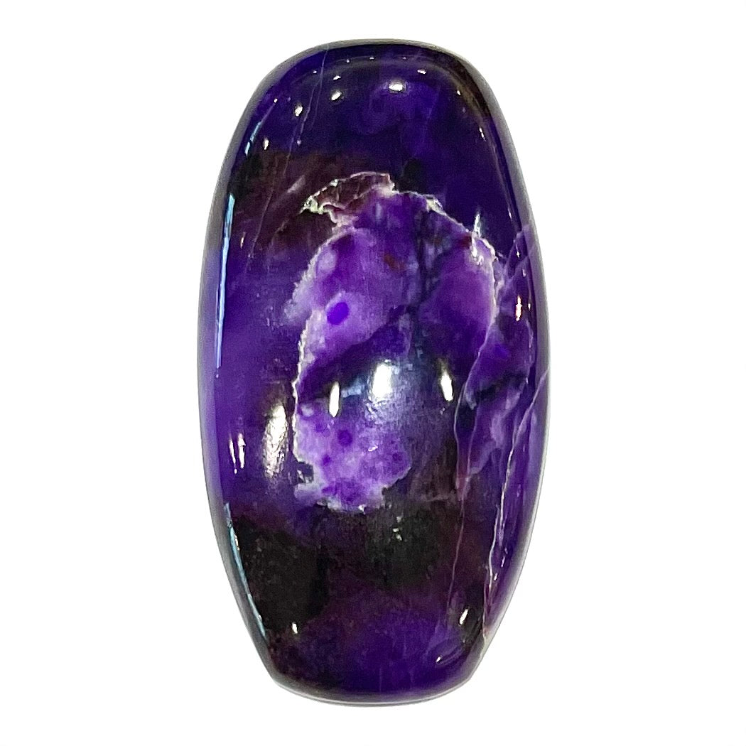 A loose, barrel cabochon cut purple sugilite stone.