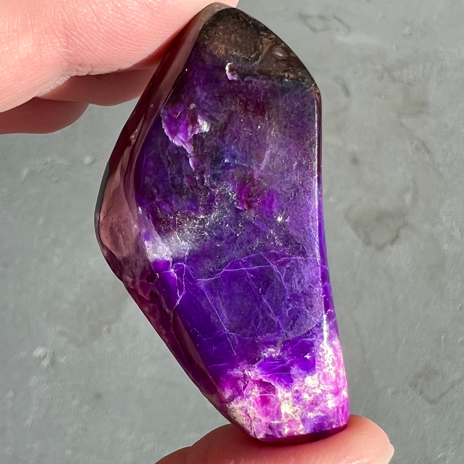 A loose, polished sugilite specimen displaying a blend of different shades of purple.