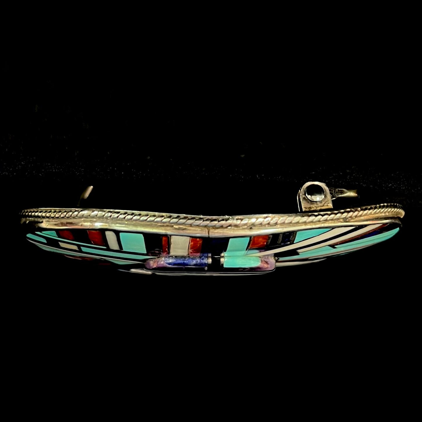 A sterling silver Zuni sunface belt buckle inlaid with lapis, turquoise, onyx, mother of pearl, coral, and sugilite stones.  It is stamped "RGB Zuni."