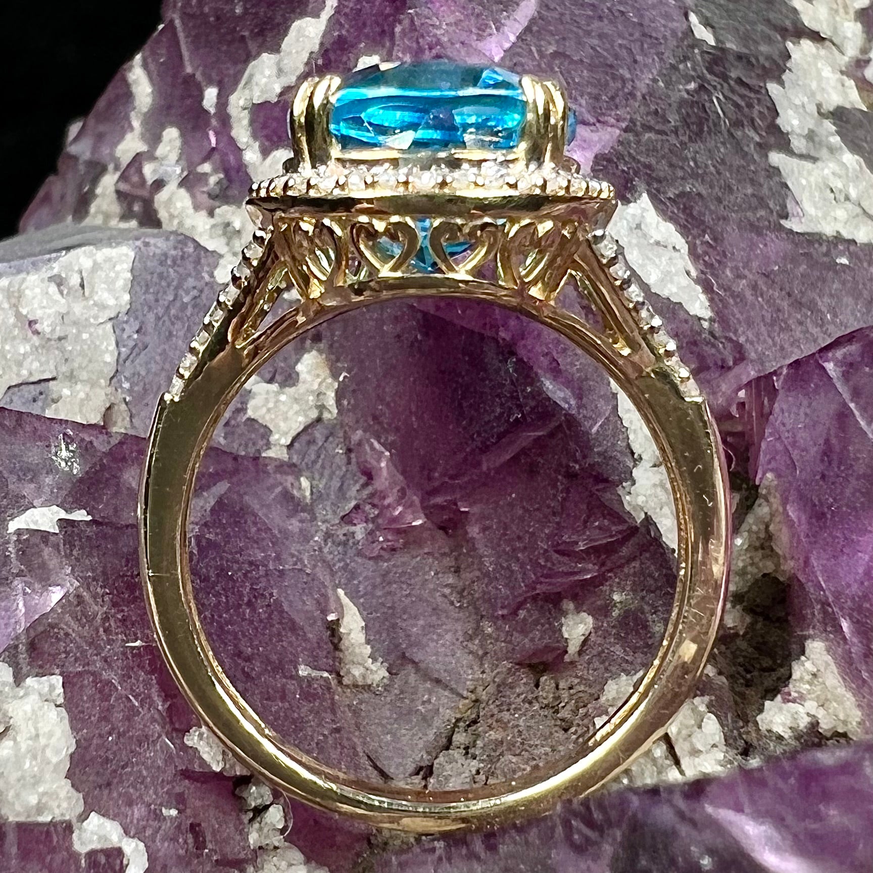 An oval cut Swiss blue topaz and diamond pave split shank ring in yellow gold.