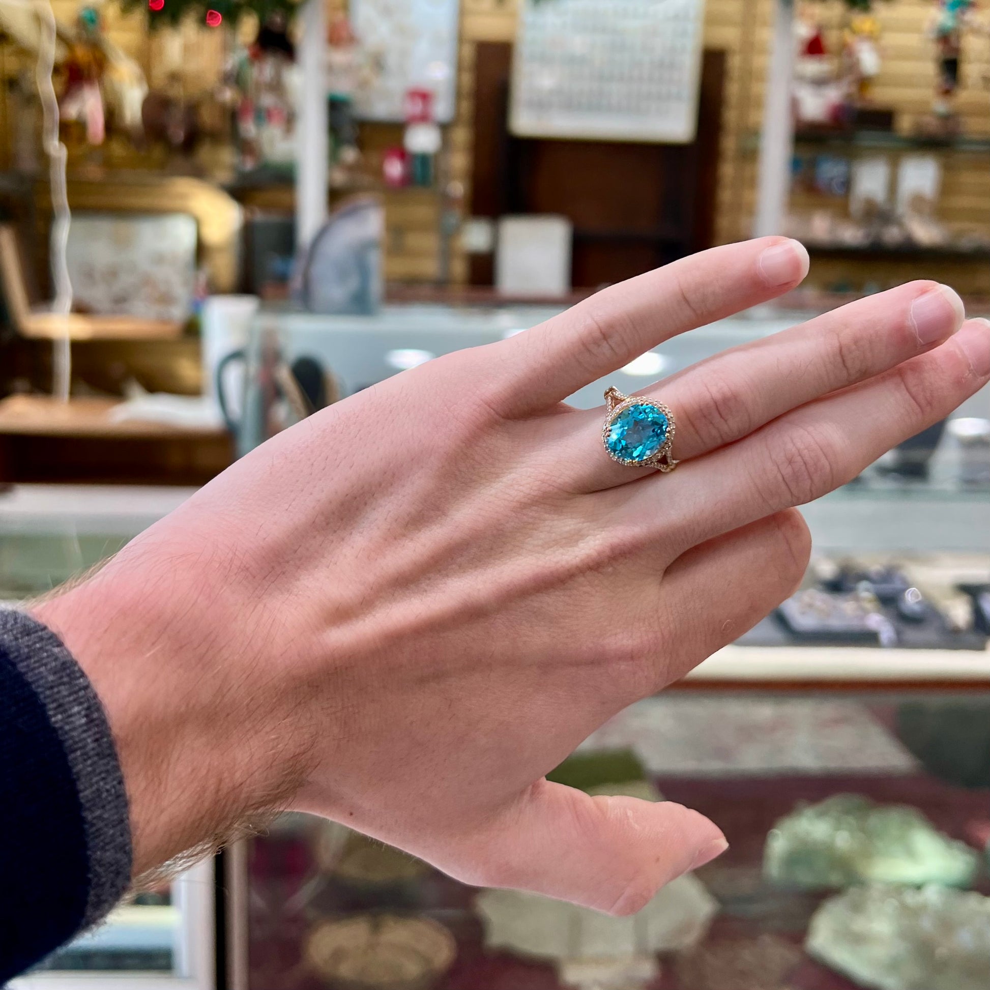 An oval cut Swiss blue topaz and diamond pave split shank ring in yellow gold.